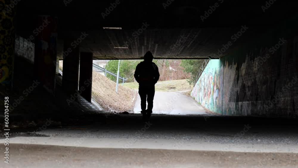 silhouette of a man walking alone in a tunnel silhouette of a man walking alone in a tunnel