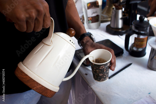 a barista holding a pot making coffee