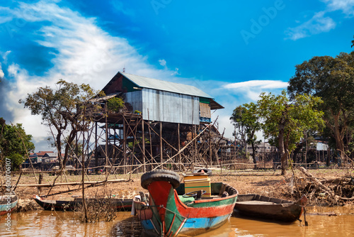 Boats and houses on stilts on rural river, Kompong Phluk floating fishing village in drought season. Tonle Sap lake, life and work cambodian people, residents poverty country Cambodia. Copy text space