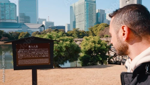 A tourist man looking at the sign at Hamarikyu Gardens which is a natural park area in Shiodome District in Tokyo, Japan photo