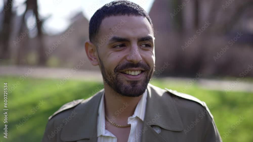 One happy Arab man closeup face walking forward toward camera smiling while at park during sunny day One happy Arab man closeup face walking forward toward camera smiling while at park during sunny day