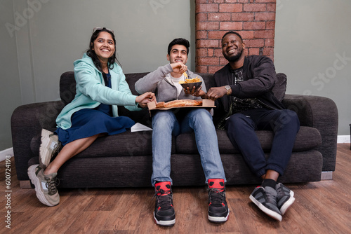Group of friends sitting on sofa and eating snacks photo