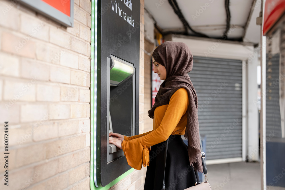 Woman in hijab using ATM Woman in hijab using ATM
