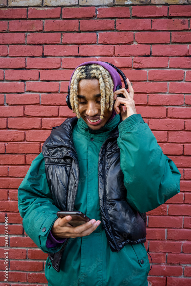 Naklejka premium Smiling young man listening to music