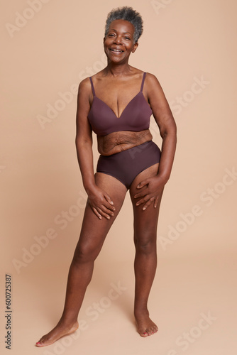Studio shot of senior woman posing in underwear against beige background