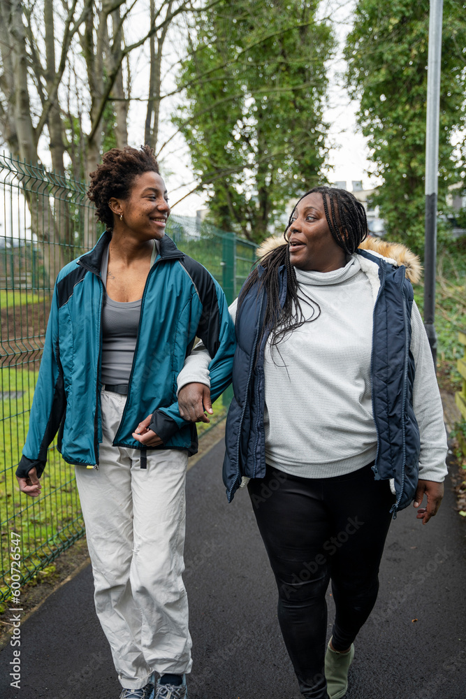 Mother and daughter talking while walking in park