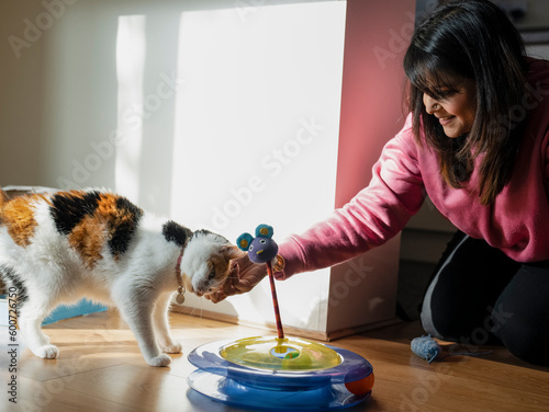 Smiling woman stroking cat at home photo