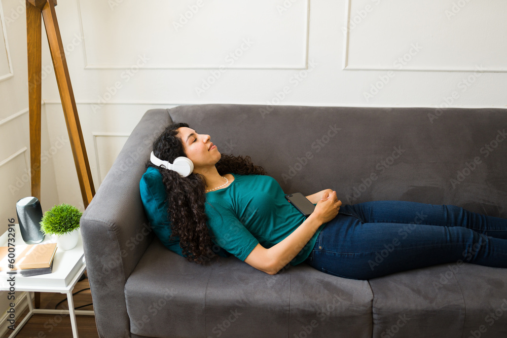 Fototapeta premium Attractive woman listening to meditation music on the couch