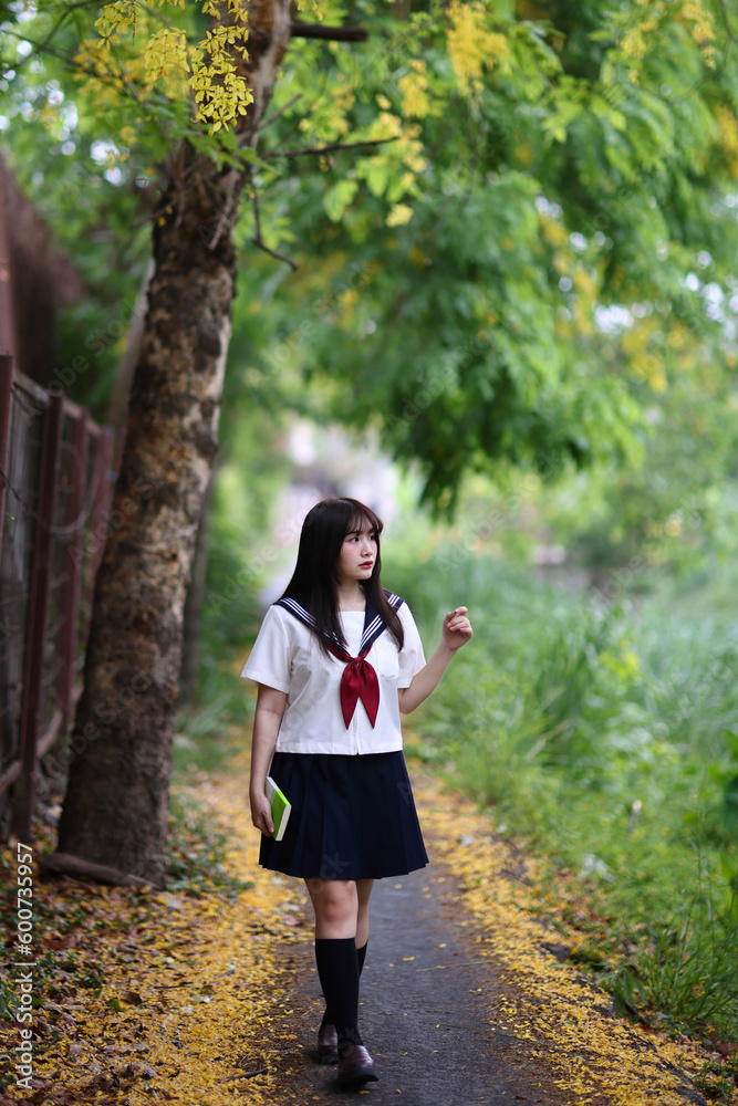 Japanese high school student walking in park with tree background Japanese high school student walking in park with tree background