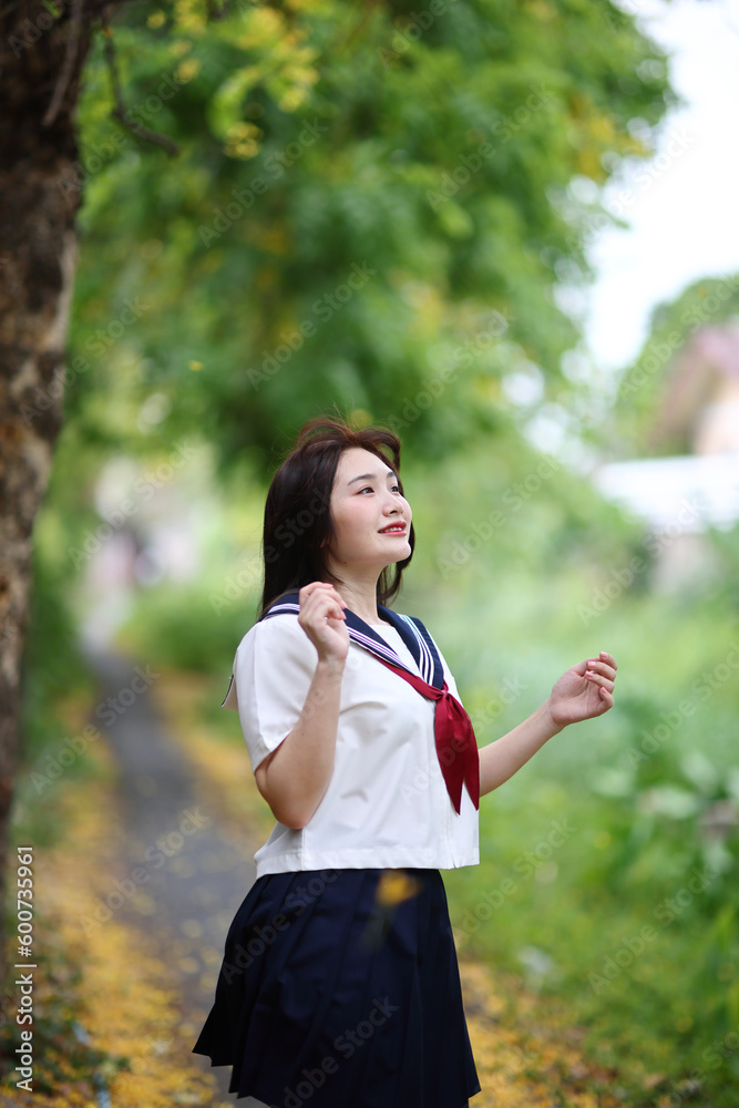 Japanese high school student looking in park with tree background Japanese high school student looking in park with tree background