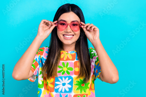 Photo of sweet positive woman dressed flower print t-shirt arms pink spectacles empty space isolated blue color background