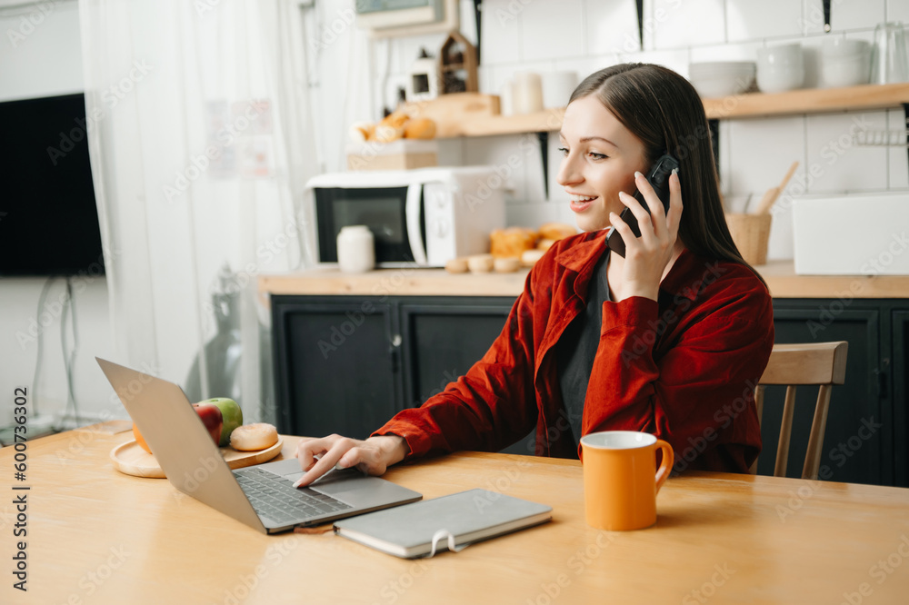 Business woman Talking on the phone and using a laptop with a smile while sitting at office Business woman Talking on the phone and using a laptop with a smile while sitting at office