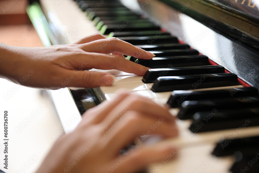 Obraz premium Close up of female hands playing a melody on piano