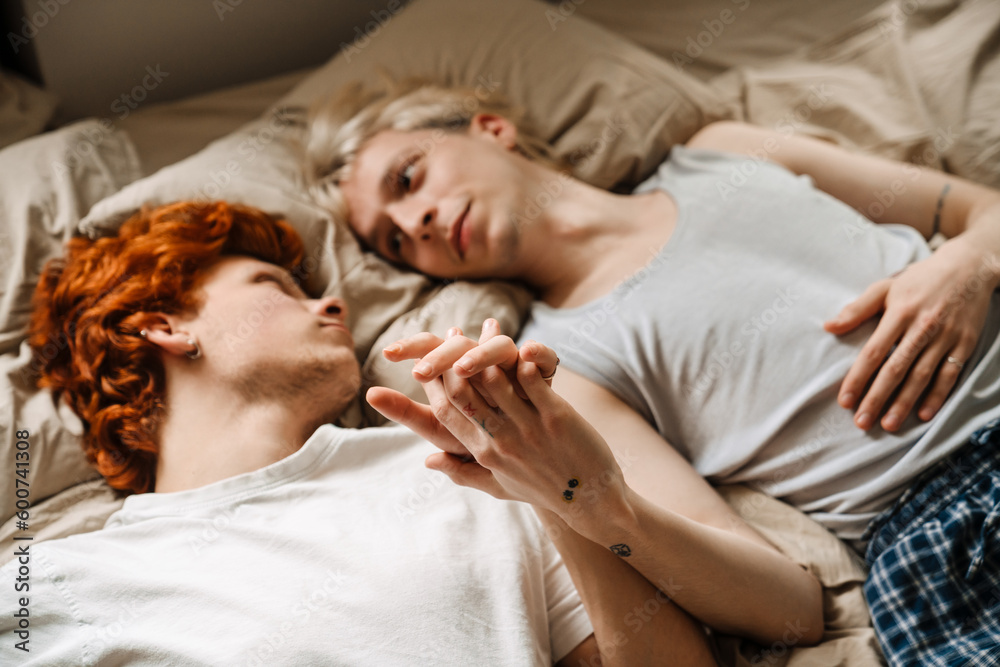 Gay couple holding hands while laying on bed Gay couple holding hands while laying on bed