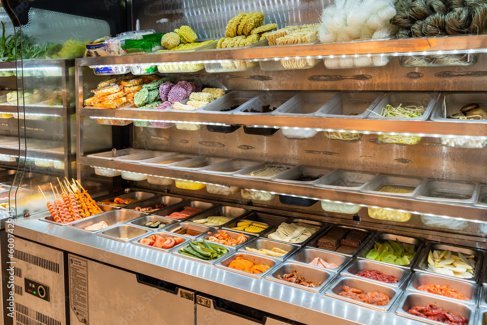 The refrigerated storage cabinet is filled with various vegetables and meats for freshness. Food in spicy hot pot shop in china.