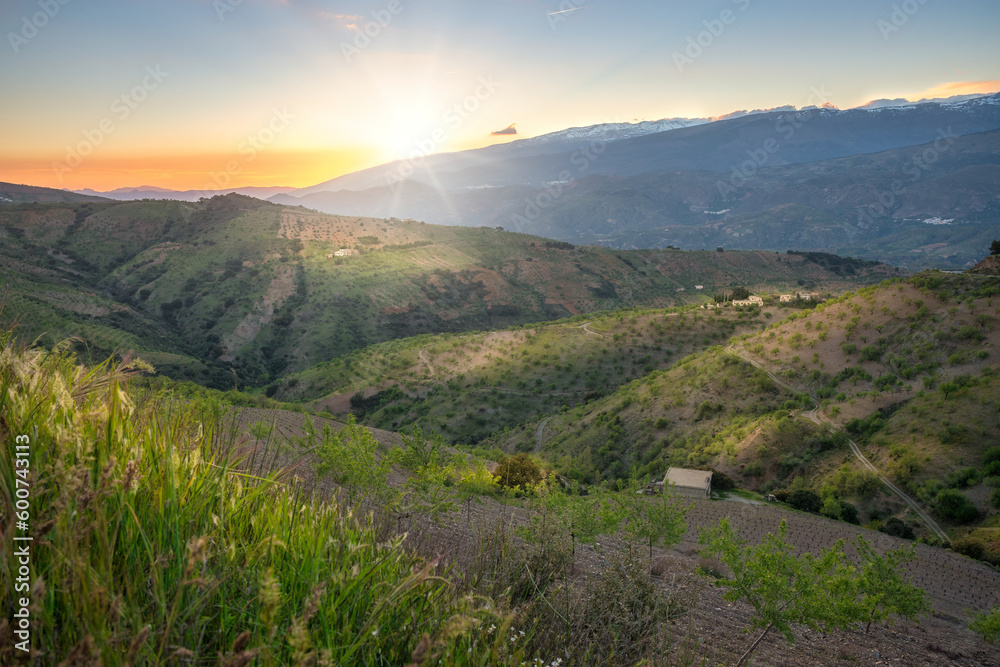 The last rays of sunlight illuminate the landscape in the Alpujarra region during a soft sunset.