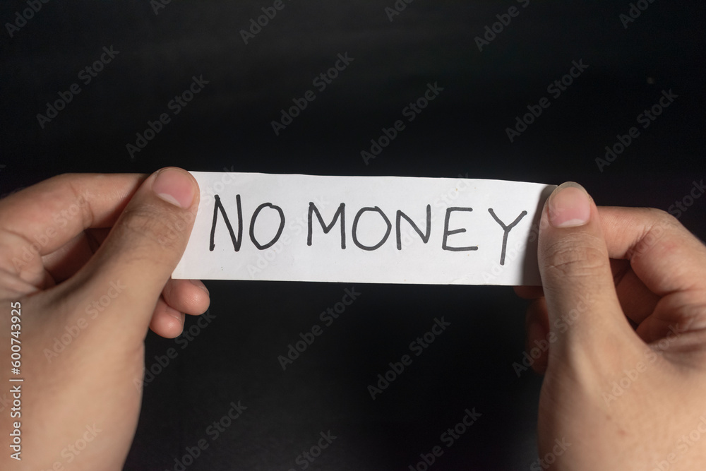 a young man hand holding a paper reads no money sign. isolated on black background