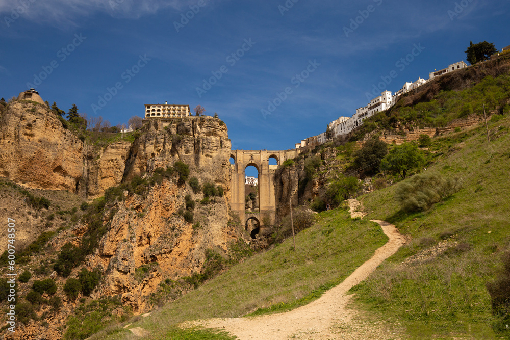 Fototapeta premium The famous bridge with arched vaults between the rocks of the gorge on a sunny day. Landmark of the city of Ronda, Andalusia, Spain