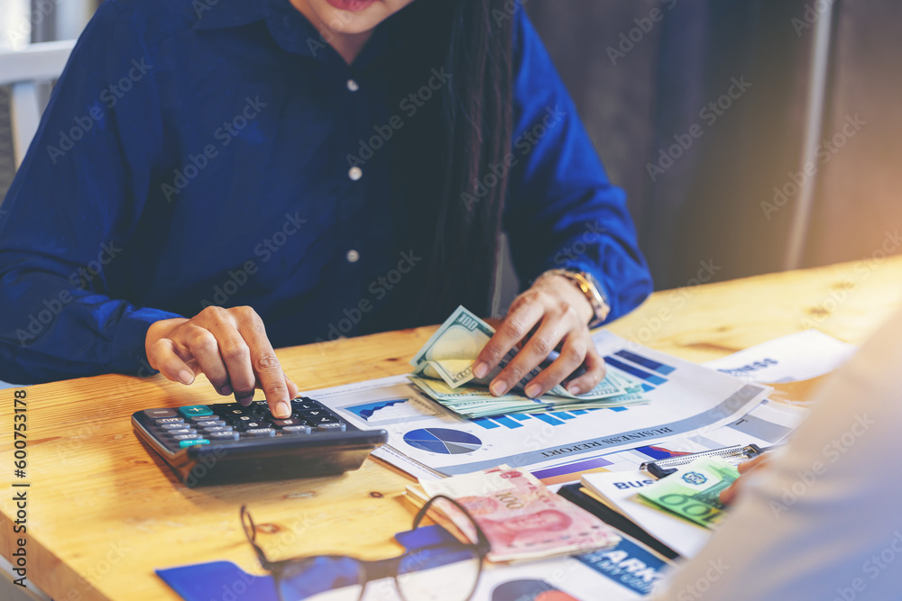 Businesswoman accountant working on desk using calculator for calculate money and checking finance report. Selected focus