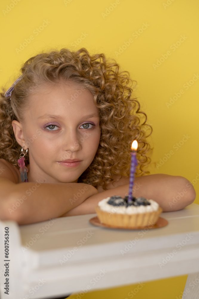 birthday with a small cake and a candle on a yellow background, afro curls, blonde birthday with a small cake and a candle on a yellow background, afro curls, blonde