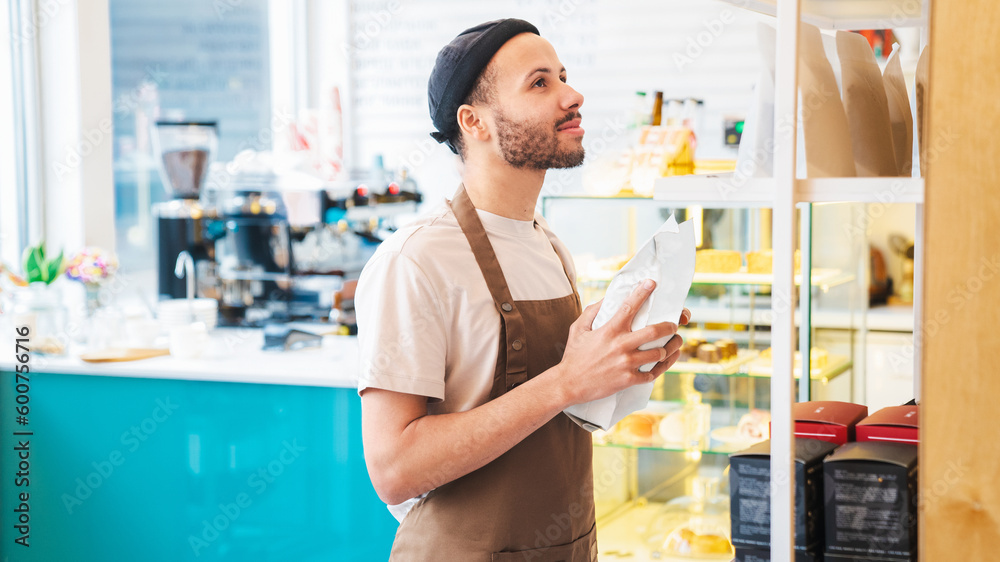 Smiling man holding package with freshly baked coffee beans Smiling man holding package with freshly baked coffee beans