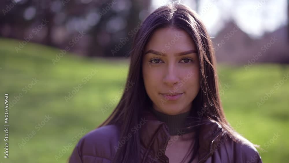 Portrait a young brunette adult girl standing outside at park looking at camera. Woman closeup face Portrait a young brunette adult girl standing outside at park looking at camera. Woman closeup face