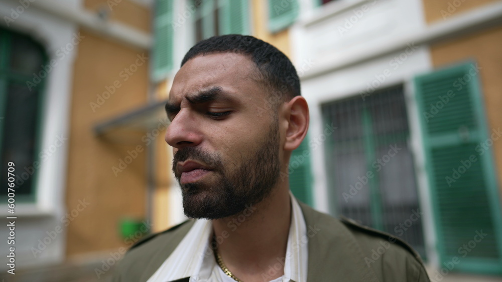Obraz premium Closeup face of an Arab man with thoughtful expression. A Pensive male person standing outside in with serious contemplative brooding emotion