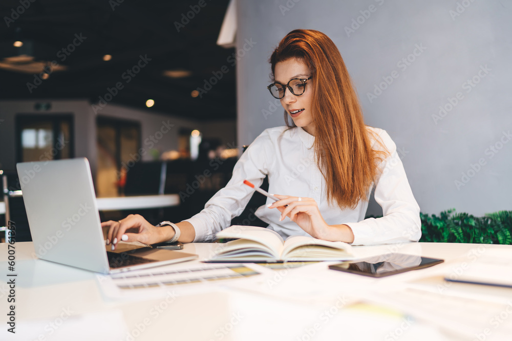 Focused woman working on netbook in workspace Focused woman working on netbook in workspace
