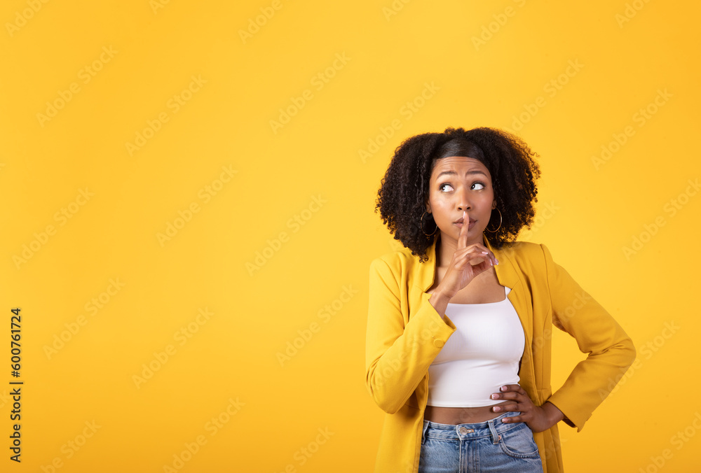 Misterious young black woman with bushy hair showing silence gesture and looking aside at copy space Misterious young black woman with bushy hair showing silence gesture and looking aside at copy space