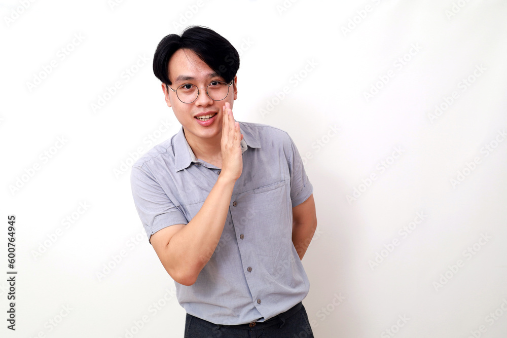 Happy asian man standing with whispering gesture. Isolated on white Happy asian man standing with whispering gesture. Isolated on white