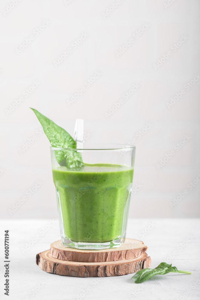 Healthy green smoothie with spinach, banana, and vegan milk in glass on light grey background. Detox, diet, healthy, vegetarian food concept, copy space, minimalism