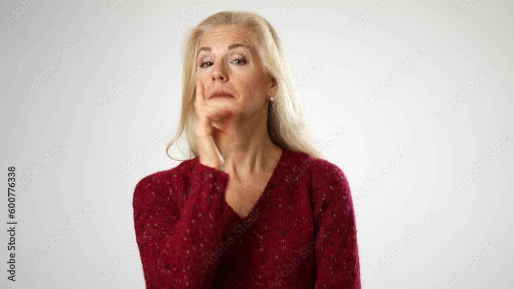 Secret smiling elderly gray-haired blonde woman 50s years old look aside close her mouth lock and throw away key isolated on solid white background studio portrait Secret smiling elderly gray-haired blonde woman 50s years old look aside close her mouth lock and throw away key isolated on solid white background studio portrait