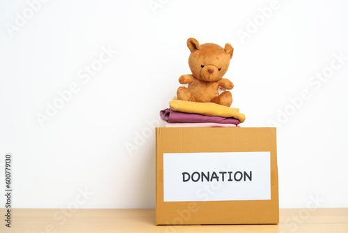 Kid Donation, Charity, Volunteer, Giving and Delivery Concept. Bear doll and Clothes with Donation box at home for support and help poor, refugee and homeless people. Copy space for text © Jo Panuwat D