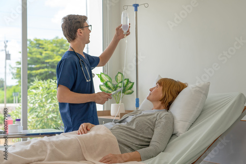 A doctor is explaining treatment guidelines to a female patient lying in IV fluid in a hospital.