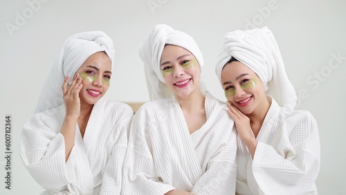 Close face group of beautiful young asian women in bathrobe and towels on heads with collagen patch on under eyes smiling to camera. Self care and daily beauty routine