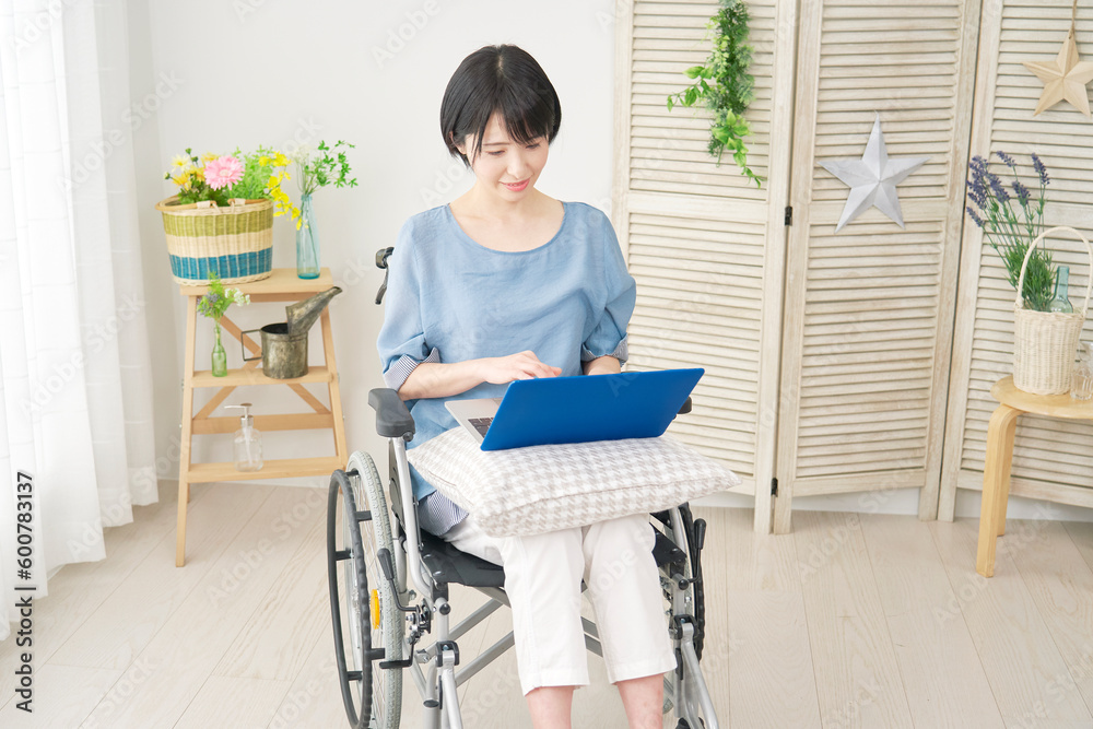 リビングでノートパソコンを使う車椅子に乗った女性