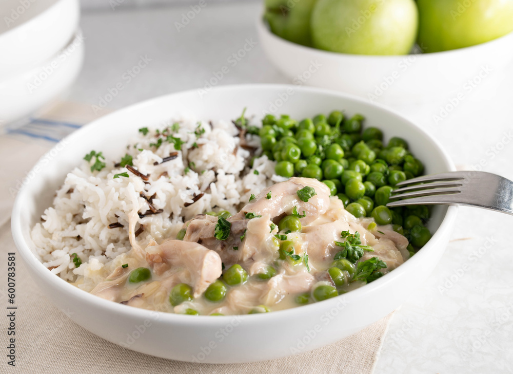 Chicken fricassee with basmati rice and wild rice. Served with buttered green peas on a plate Chicken fricassee with basmati rice and wild rice. Served with buttered green peas on a plate