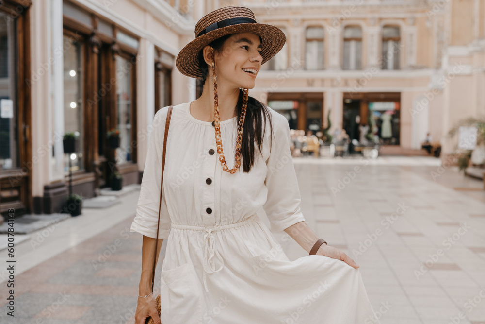 Obraz premium attractive woman walking in shopping street in Italy on vacation dressed in white summer fashion dress