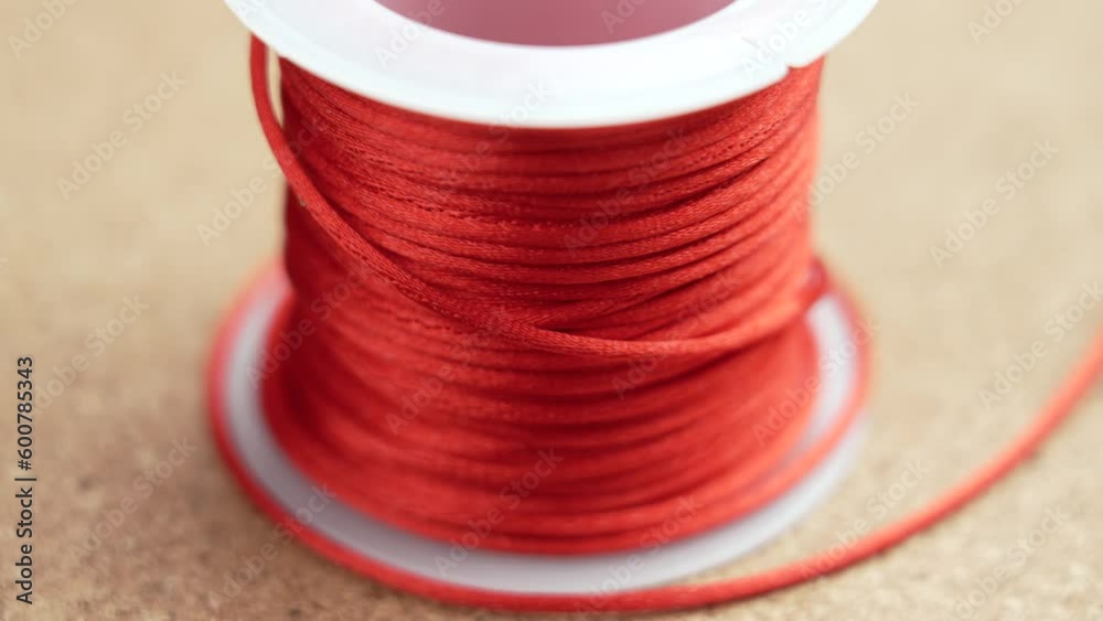 Red colorful string on a white spool close up. Macro. Rotation