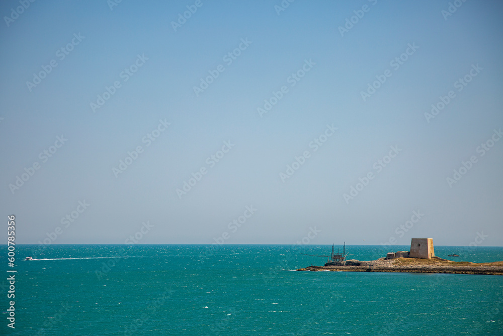 A castle tower on the coast the Adriatic Sea with a white boat on the water