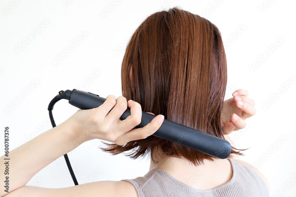 Fototapeta premium ストレートアイロンを使う女性 ヘアセット