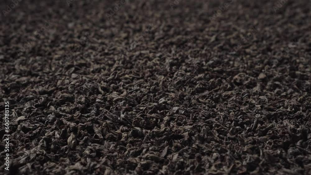Background of black fanning or broken loose leaf tea slowly rotating. Close-up, angled view