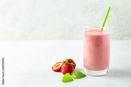 Healthy protein strawberry smoothie, yogurt milkshake in glass with mint leaves.