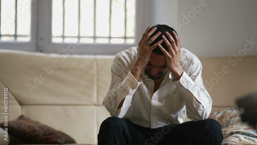 Dramatic young man feeling distraught and stressed from emotional pressure. Frustrated male person sitting at home hitting couch with hand acting aggressive