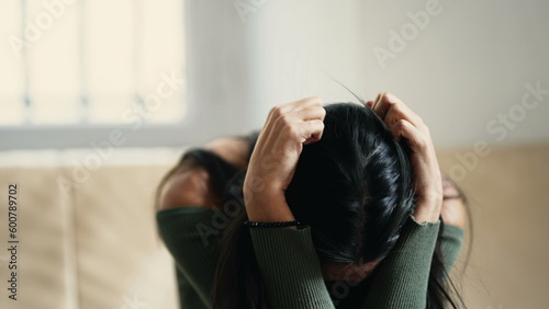 Distressed young woman overwhelmed with anxiety and sadness, feeling helpless and lost at home