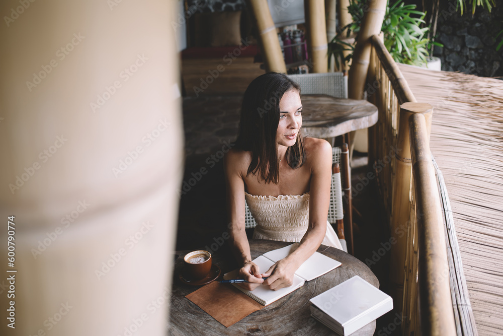 Young woman sitting at table coffee cup pen and notepad in cafe