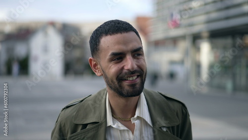A content Arab man strolls down city. Tracking shot of a thoughtful Middle Eastern male wearing a jacket portrait face closeup in motion