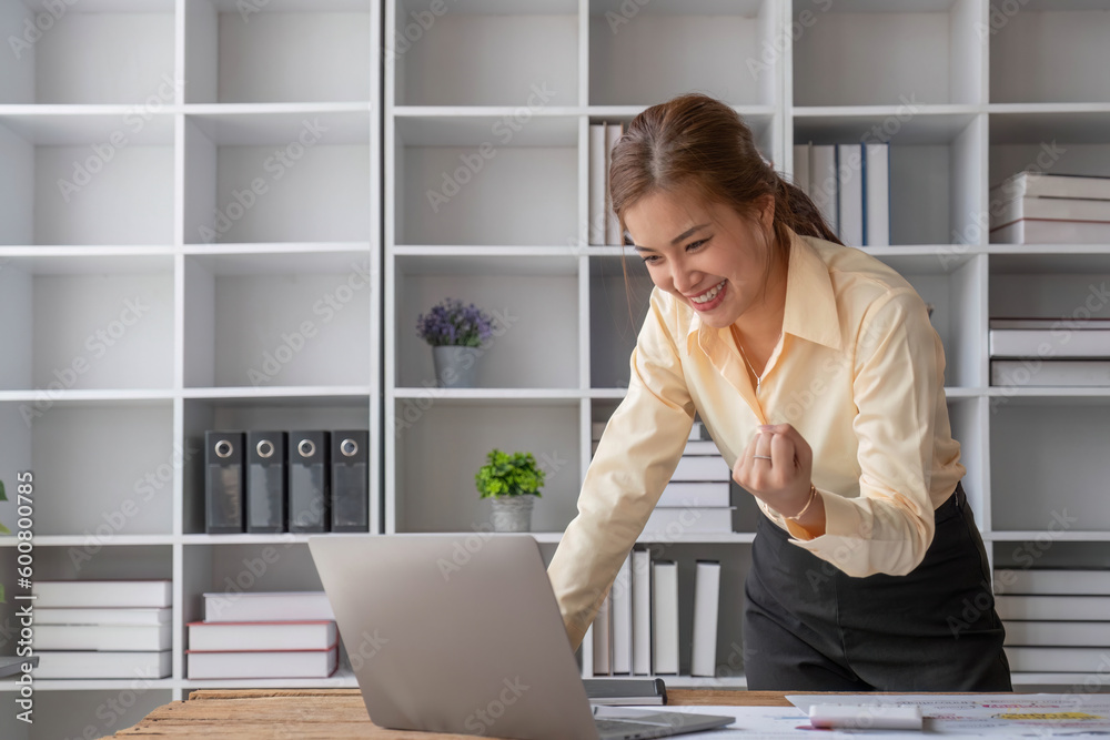 Beautiful Asian businesswoman celebrate while using laptop at office and showing delight. Startup small business and successful concept. Beautiful Asian businesswoman celebrate while using laptop at office and showing delight. Startup small business and successful concept.