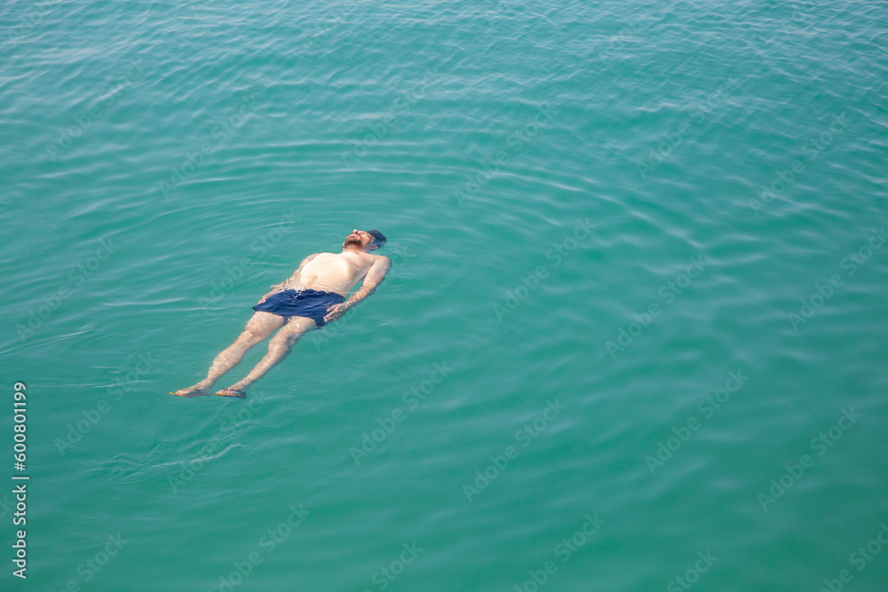 A man floating in the sea, top view.