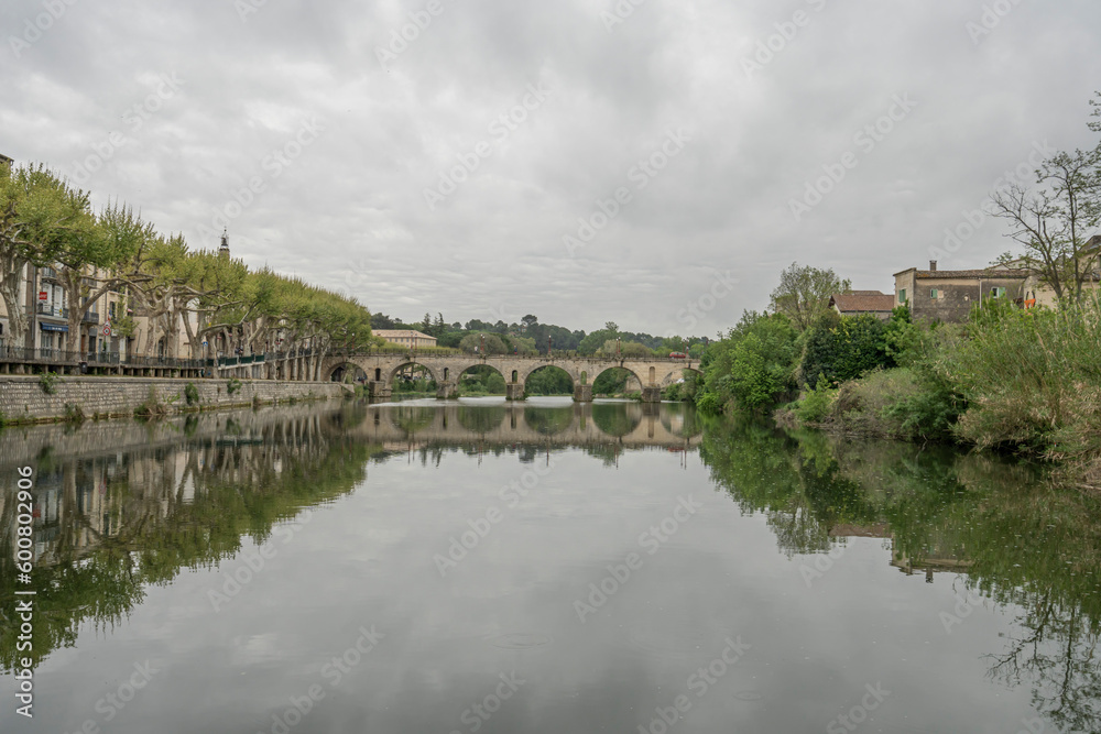 Sommieres, France - 04 22 2023: View of the Sommieres Roman bridge reflecting in the Vidourle river